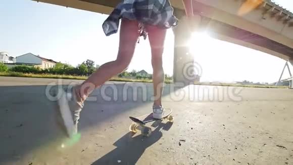 美丽的女孩骑着滑板在车架上修长的腿阳光阳光视频的预览图