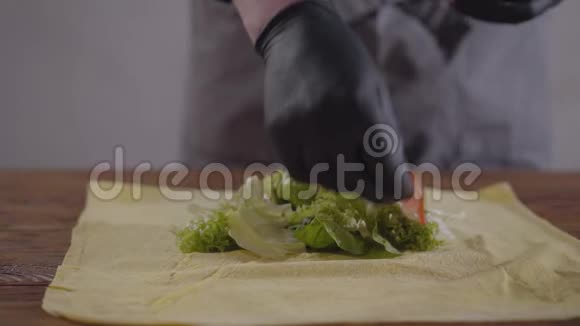 厨师的双手戴着黑色厨房手套制作沙瓦玛特写厨师把西红柿和洋葱放在皮塔上视频的预览图
