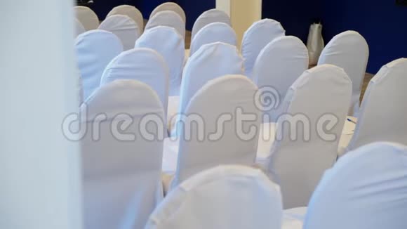 在婚礼会议或研讨会的大厅里一排排着白色罩布的椅子视频的预览图