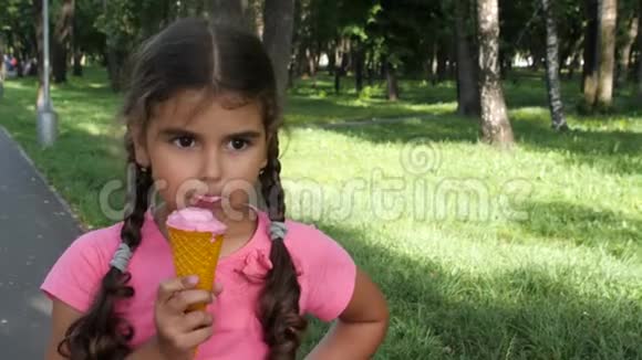 5岁的女孩在户外吃冰淇淋一个梳着辫子的漂亮卷发女孩在华夫饼筒里吃冰淇淋视频的预览图