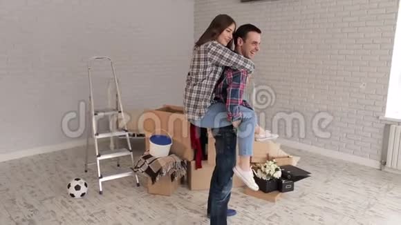 一个快乐的女孩跳上了她在一个新公寓里快乐的男人的背上新家视频的预览图