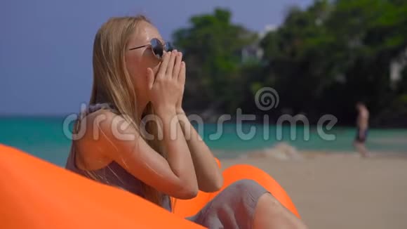 年轻女子一边咳嗽一边坐在热带海滩的充气沙发上旅行疾病概念视频的预览图