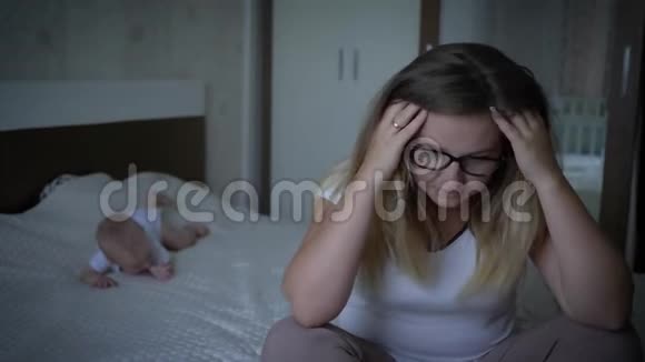 女人厌倦了孩子不开心紧张的年轻妈妈抱着头躺在床上的背景孩子视频的预览图