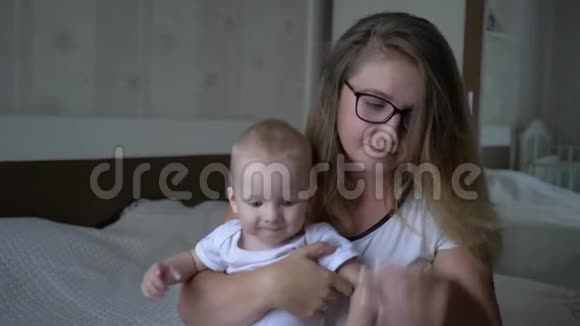 不开心疲惫的女人抱着小男孩看着相机坐在家里的床上视频的预览图