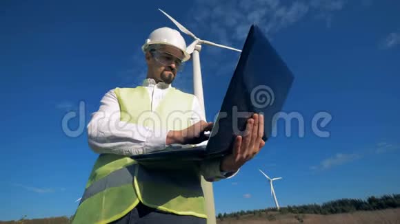 工人站在风力涡轮机附近手提电脑关闭视频的预览图