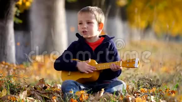 有趣的孩子在吉他边唱歌的肖像快乐的孩子在公园里拍手视频的预览图