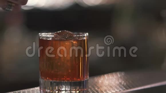 男性用手将橘子片放入玻璃杯中并将鸡尾酒或威士忌放近视频的预览图