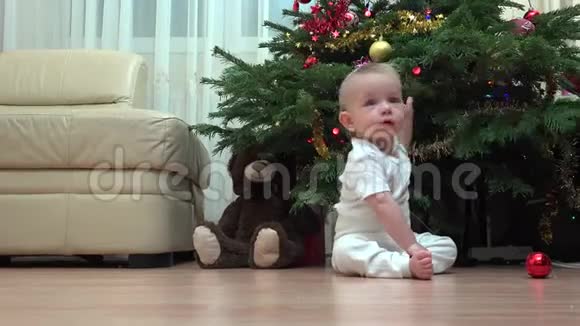 有趣的宝宝坐在圣诞树下玩装饰孩子爬视频的预览图