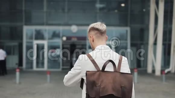 在工作的商人英俊的年轻人穿着白色衬衫背着背包跑到机场看着钟旅费视频的预览图