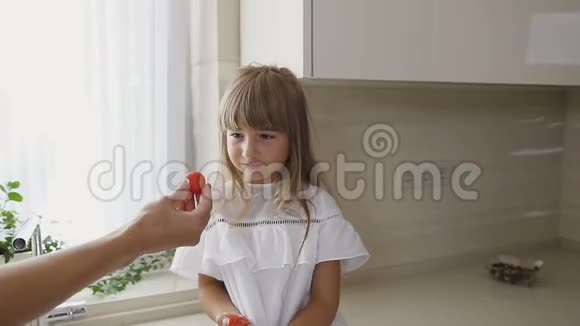 一个女人在吃饭前洗蔬菜她可爱的女儿坐在她旁边吃西红柿健康食品概念视频的预览图