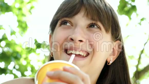 公园里十几岁的女孩正在喝一杯稻草鸡尾酒正笑着特写镜头视频的预览图