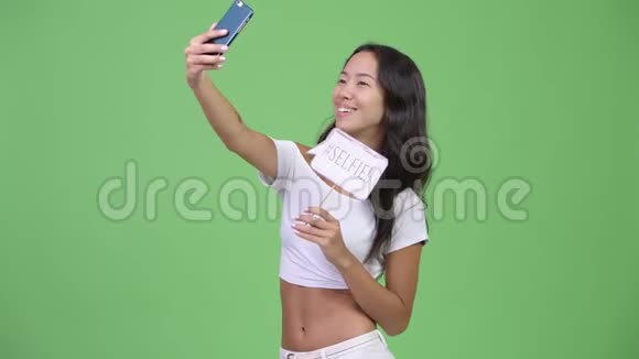 年轻快乐美丽多民族的女人用纸签自拍视频的预览图
