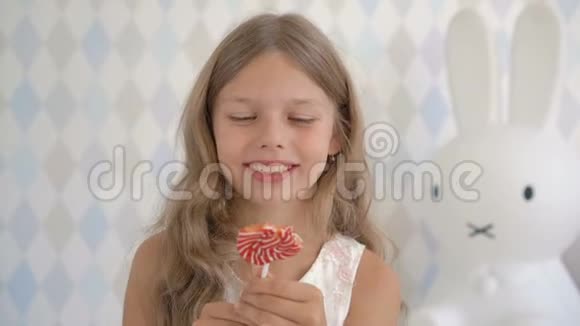 有趣的孩子带着糖果棒棒糖快乐的小女孩吃棒棒糖孩子在家吃糖果视频的预览图