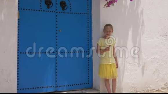 带着冰淇淋的少女在白色的背景墙上摆着蓝色的门视频的预览图