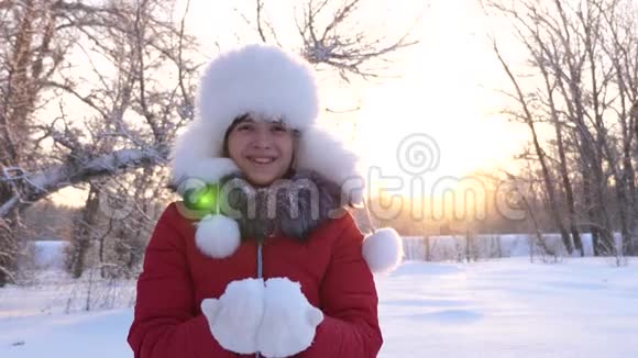 圣诞节假期孩子们在冬天的公园里用手吹雪花快乐的女孩在日落时吹雪花视频的预览图