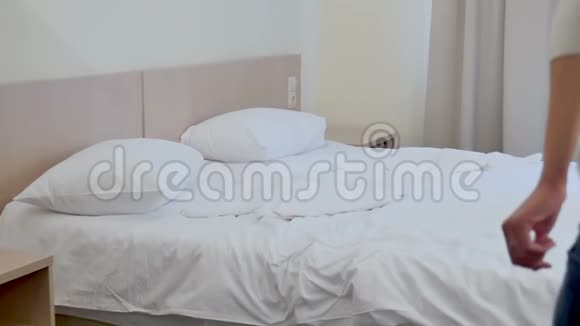 年轻的金发女人在白色的酒店床上跳跃视频的预览图