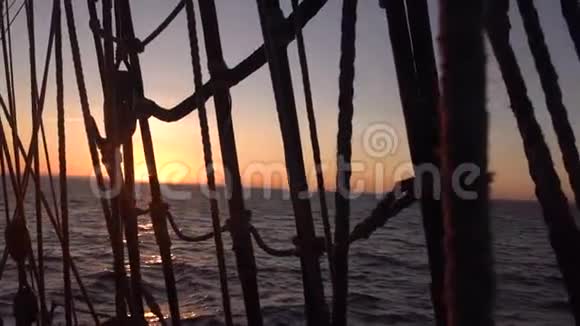 太阳落山穿过一艘旧帆船的船罩和帆索视频的预览图