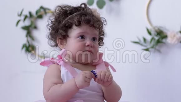 穿着粉色连衣裙手中拿着一朵花在摄影棚特写镜头上拍照的婴儿视频的预览图