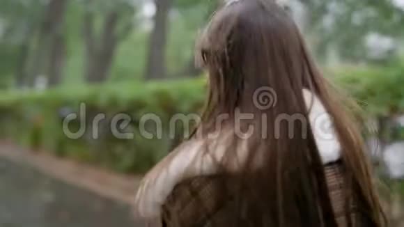 从背后看一个时髦的年轻女孩穿着格子棕色外套走在外面秋天视频的预览图