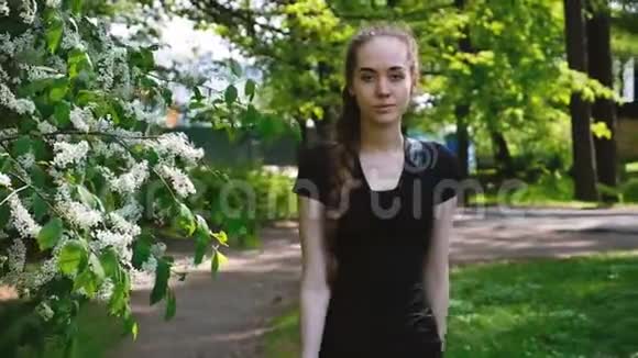 美丽的年轻女孩带着长长的辫子在公园里散步在镜头前直走慢动作具有吸引力的欧洲视频的预览图