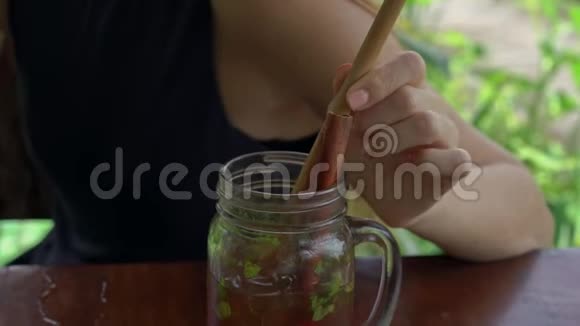 一位年轻女子在一家有稻田背景的街头咖啡馆喝着冰茶和薄荷和柠檬视频的预览图