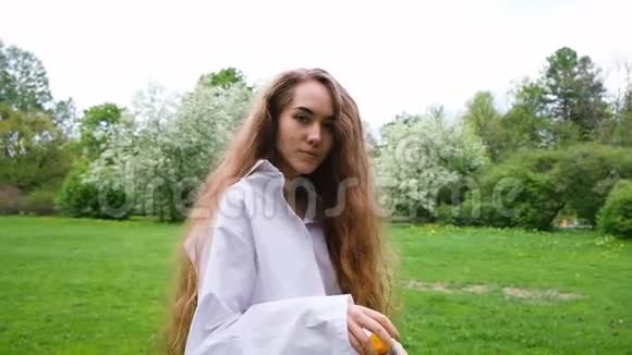 欧洲女孩长着非常长的卷发让泡泡和运行在大自然年轻的女模特在公园里玩得很开心视频的预览图