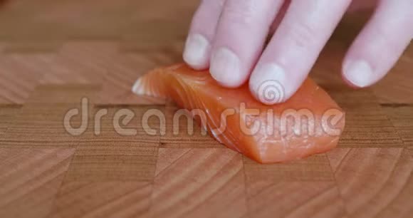 寿司主厨拿起一把刀用一把锋利的刀切下日本生鱼片和寿司用的脂肪肚三文鱼薄片视频的预览图