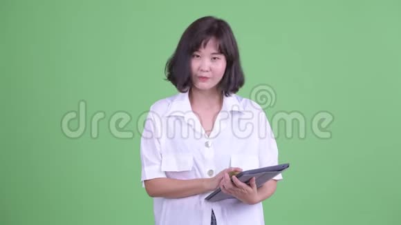 快乐美丽的亚洲女商人用数码平板电脑说话视频的预览图