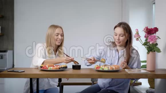 两个可爱的年轻女孩吃寿司卷聊天朋友一起在厨房视频的预览图
