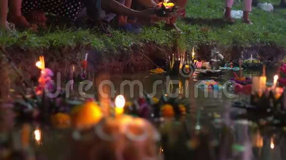 人们个人把一支燃烧着的蜡烛放在满是漂浮充满漂浮的克拉通的水中庆祝泰国传统节日视频的预览图