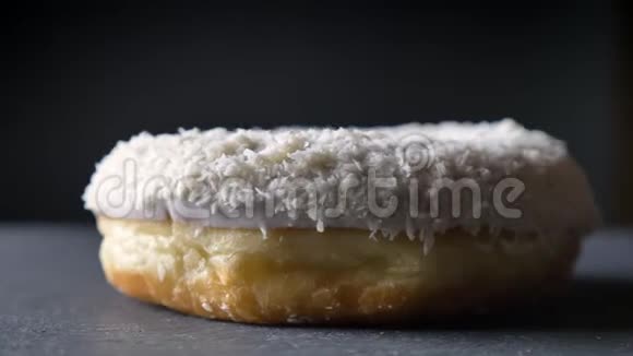 特写镜头围绕着美味的白甜甜圈椰子片在灰色的桌子背景上慢慢旋转视频的预览图