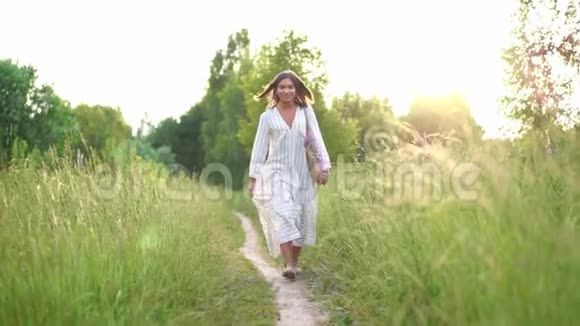 戴着牙套的女人在田野上的夕阳上微笑穿着浪漫的连衣裙会飞的头发室外视频的预览图