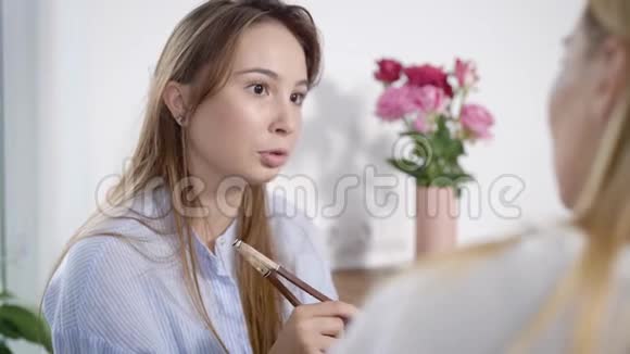 一幅漂亮的黑发女孩和一个拿着筷子的厨房里的朋友说话的肖像女孩的时间视频的预览图