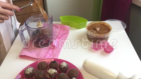 一个女人在搅拌机里加入蜂蜜里面有坚果和干果用来研磨做糖果视频的预览图