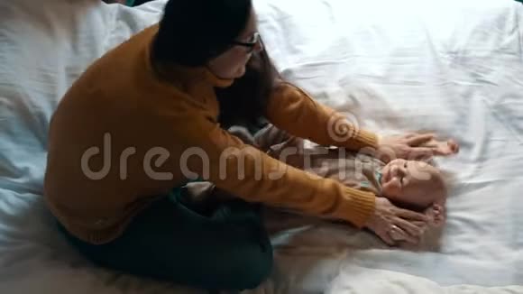 可爱的妈妈在床上和婴儿玩耍新生儿微笑母亲视频的预览图