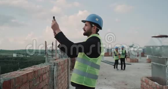 建筑师在建筑背景建筑工人的屋顶上制作图片分析施工现场的平面图4k视频的预览图