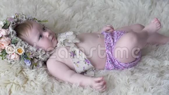 穿着花圈的漂亮小女孩躺在地毯上在摄影镜头上摆姿势视频的预览图