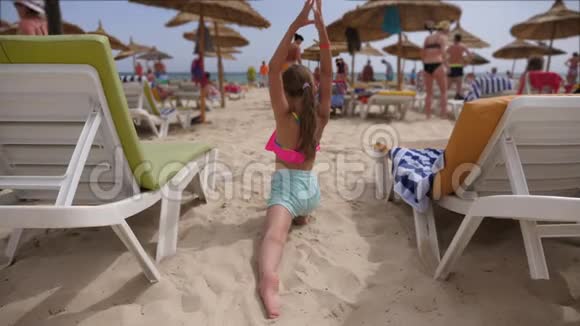 小女孩在海滩上用鸽子姿势做瑜伽视频的预览图