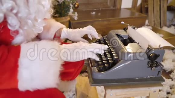 圣诞老人正在用打字机打印这封信坐在的圣诞树之间喝着牛奶听着视频的预览图