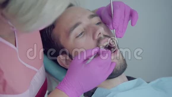 牙医在医疗面罩和手套检查病人的嘴使用医疗工具女性专业医生视频的预览图