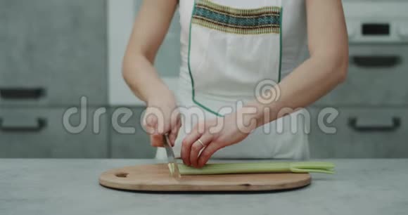 在一个现代的厨房里女人在镜头前用刀切了一根大芹菜视频的预览图