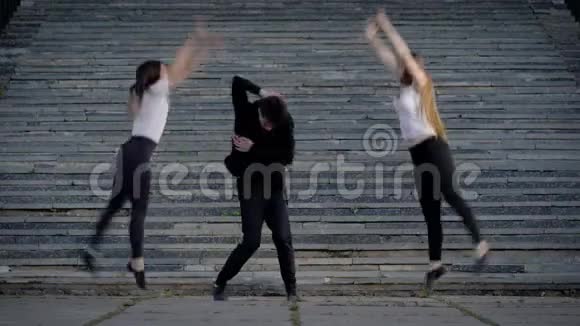 当代舞者在户外表演两个女孩和一个男人在广场上跳舞视频的预览图