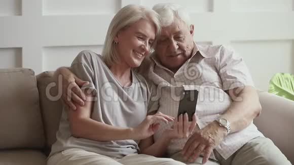快乐的老夫妇笑着用智能手机搞笑应用视频的预览图