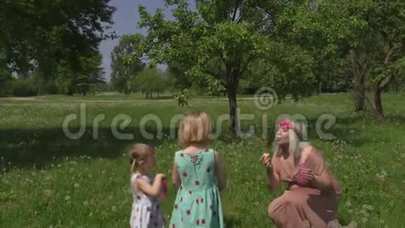 年轻的金发嬉皮士妈妈在公园里和她的小女孩一起吹肥皂泡女儿穿视频的预览图