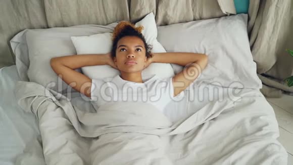 美丽的非裔美国女孩躺在床上看着上面然后闭上眼睛睡着了卧床时间视频的预览图
