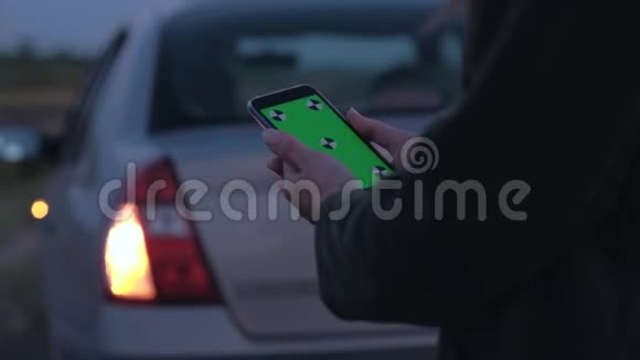 女人拿着一部智能手机在破车的背景上有绿色的屏幕视频的预览图