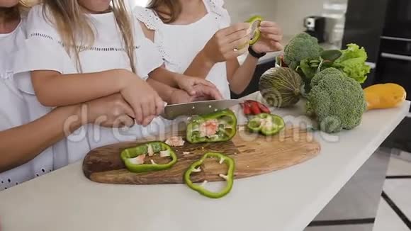 特写镜头的女子和女儿用菜刀学切青椒蔬菜视频的预览图
