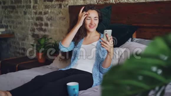漂亮的女人在网上和朋友聊天用智能手机打视频电话她很高兴也很兴奋年轻女士视频的预览图