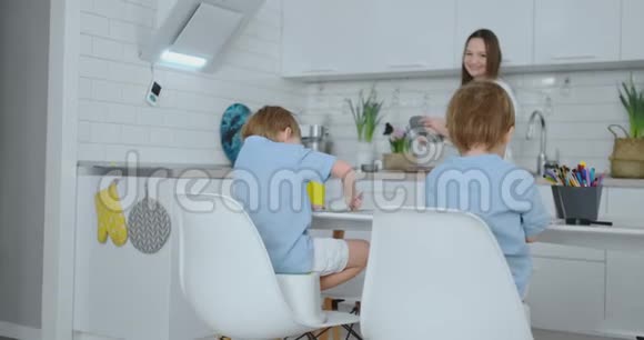 两个男孩坐在厨房的灯光上画铅笔图纸供学校索取妈妈看着孩子们微笑着视频的预览图