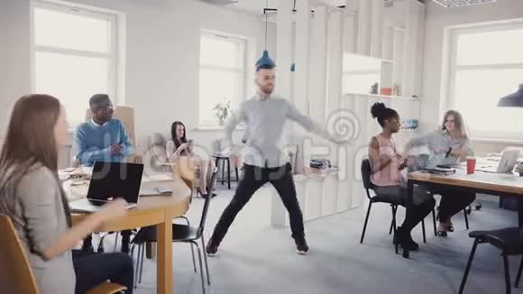 年轻快乐的商人做胜利之舞庆祝团队成功与混合种族员工在现代办公室4K视频的预览图